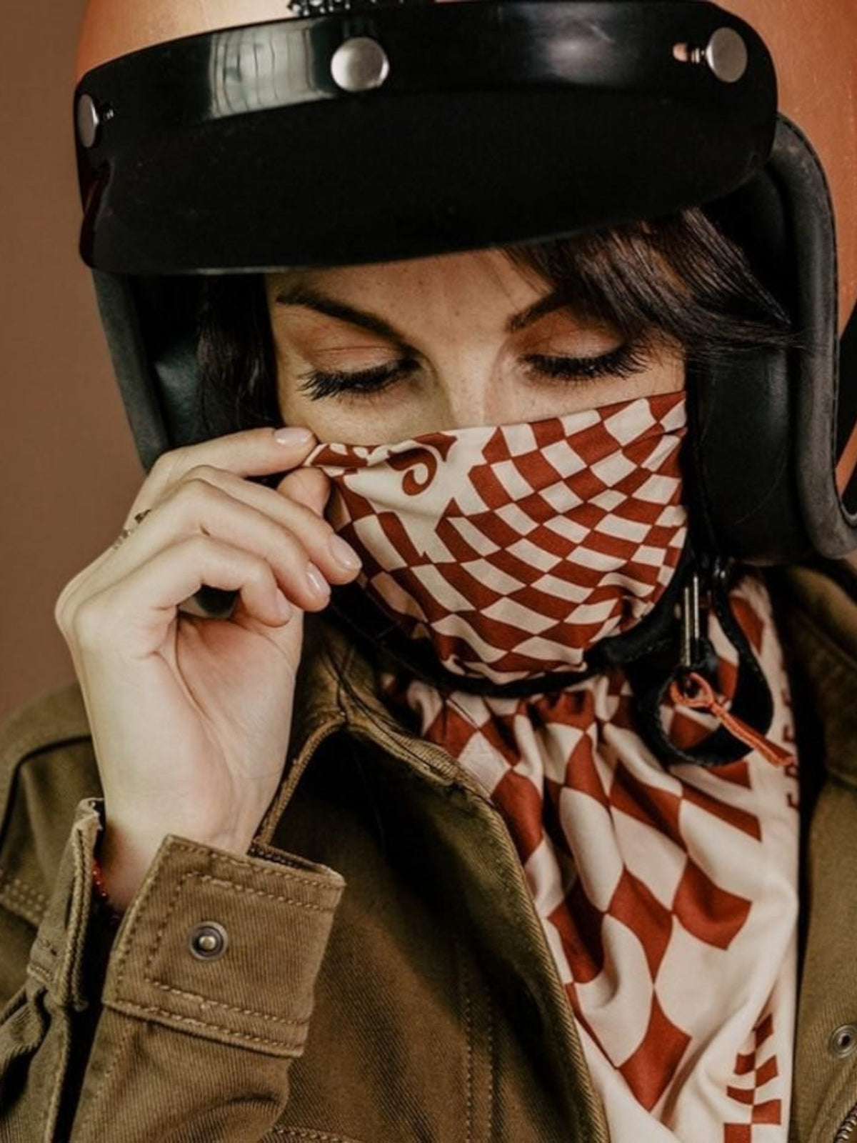 Baffle Haus terracotta and cream checkerboard motorbike scarf worn by a woman under a vintage helmet