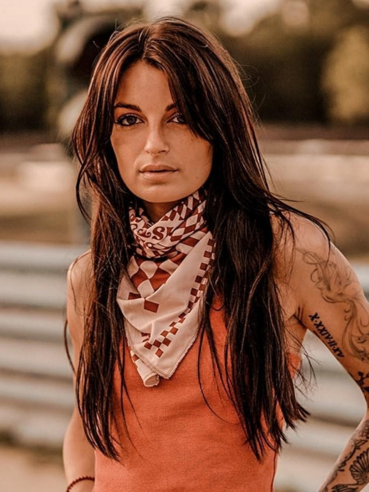Baffle Haus Petrol Junkies scarf in terracotta with a retro checkerboard pattern worn by a woman outdoors