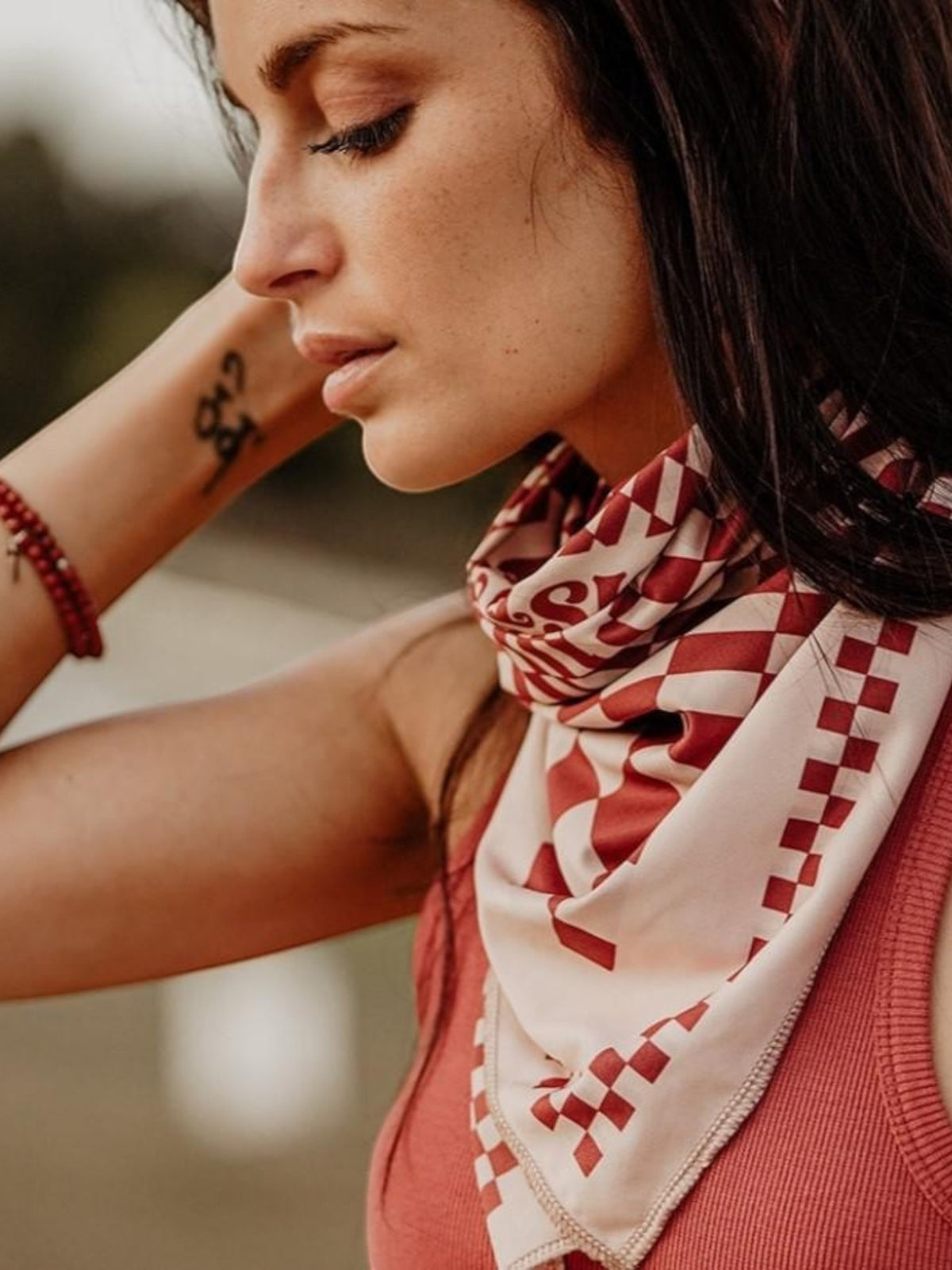 Baffle Haus Petrol Junkies scarf in terracotta and cream with a vintage racing checkerboard pattern worn by a woman.
