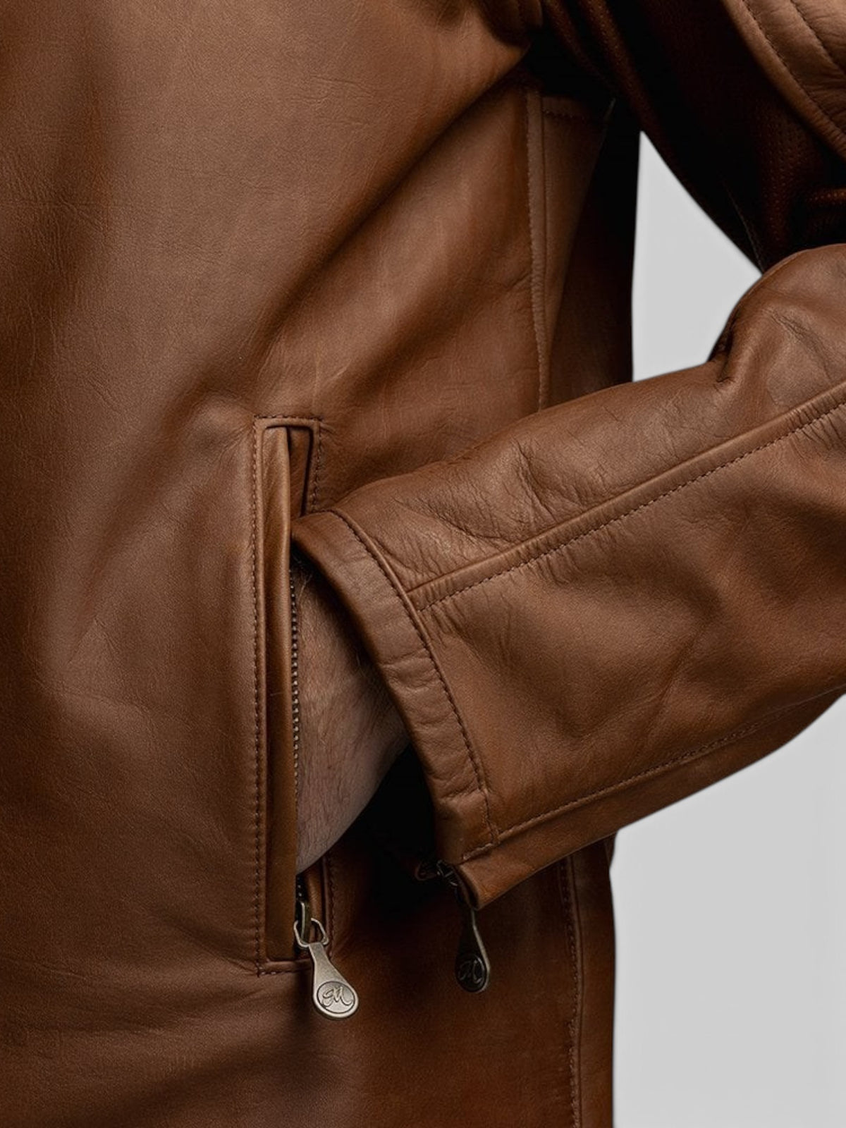 Close-up of the Baffle Haus Motone Revolver tobacco leather jacket showing the zippered hand-warmer pocket and cuff.