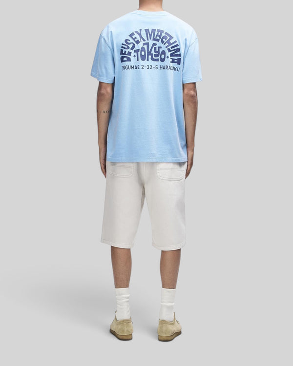 Baffle Haus Tokyo Address Tee in bonnie blue recycled cotton with back graphic print, worn with cream shorts
