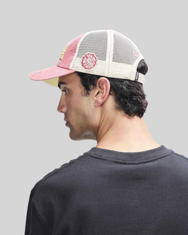 Baffle Haus Tokyo Address trucker hat in melon red with white mesh back, worn by a man in profile view.