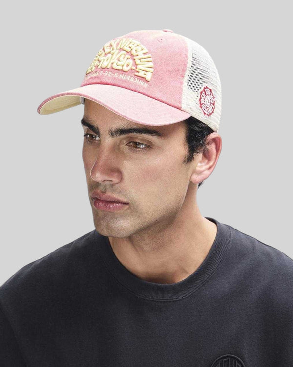 Baffle Haus Tokyo Address trucker hat in melon red with white mesh back, contrast stitching, and embroidered front logo.