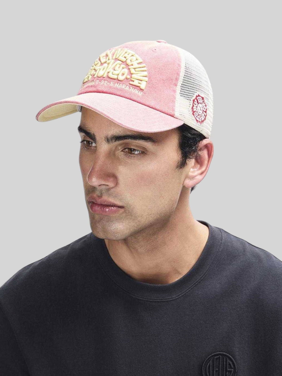 Baffle Haus Tokyo Address trucker hat in melon red with white mesh back, contrast stitching, and embroidered front logo.