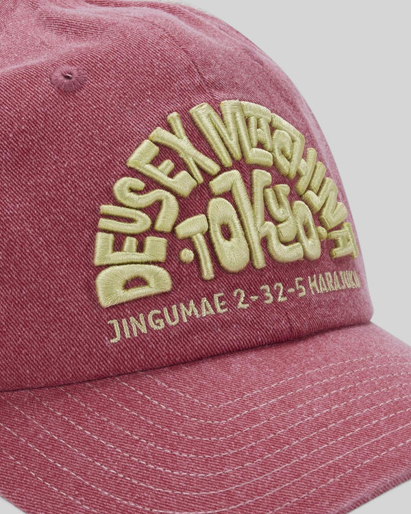 Baffle Haus Tokyo Address trucker hat in melon red with heavy enzyme wash, contrast stitching, and yellow embroidery.