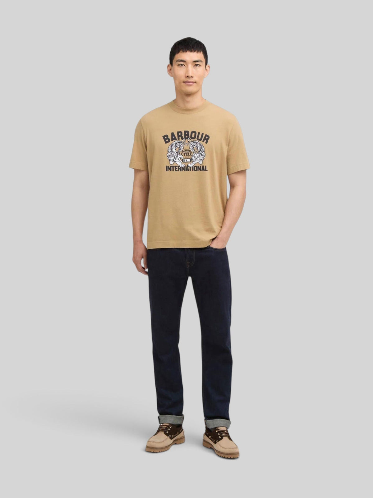 Baffle Haus model wearing a trench-coloured B.Intl Talisman graphic cotton t-shirt with dark jeans and boat shoes.