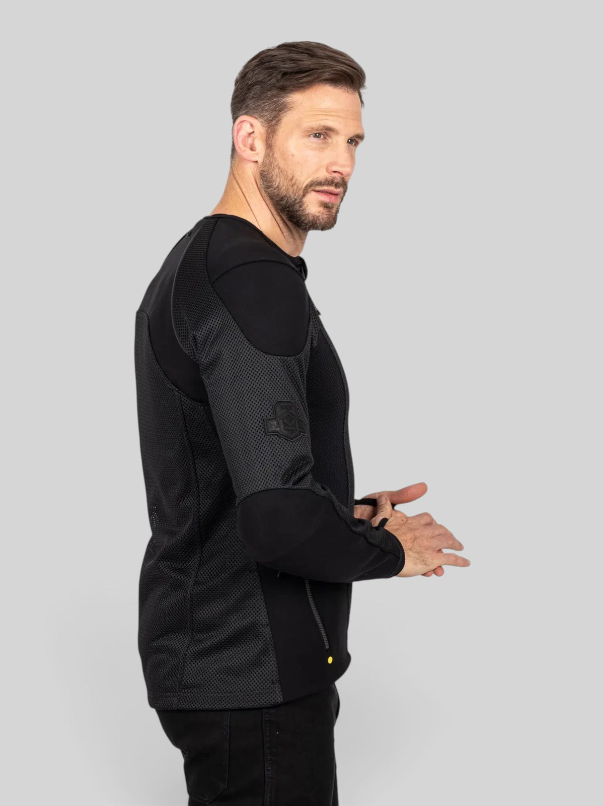 Baffle Haus Urbane Pro MK3 black motorcycle protective mesh jacket worn by a man in a side profile view