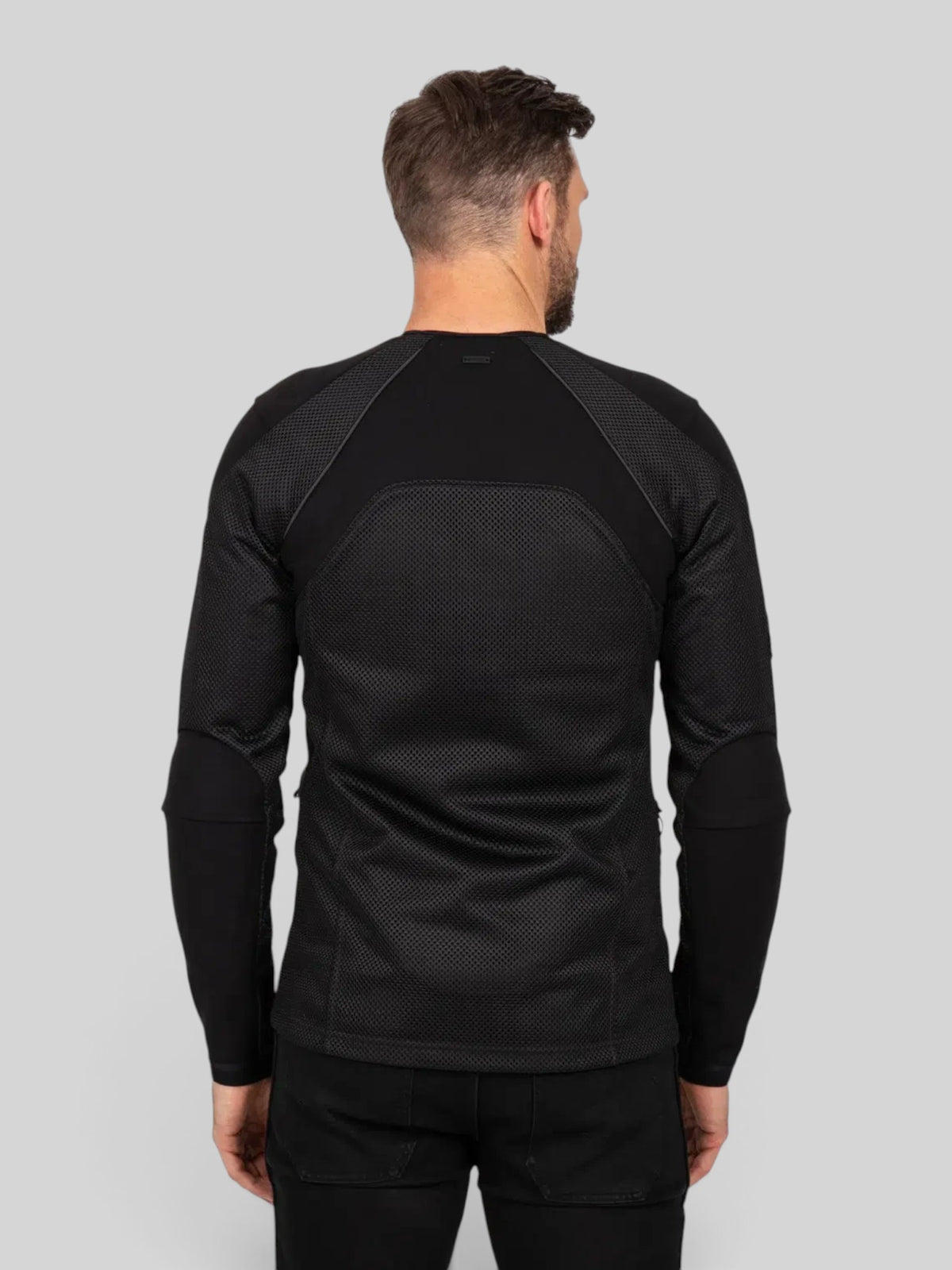 Back view of a man wearing the black Baffle Haus Urbane Pro MK3 protective motorcycle shirt with mesh paneling.