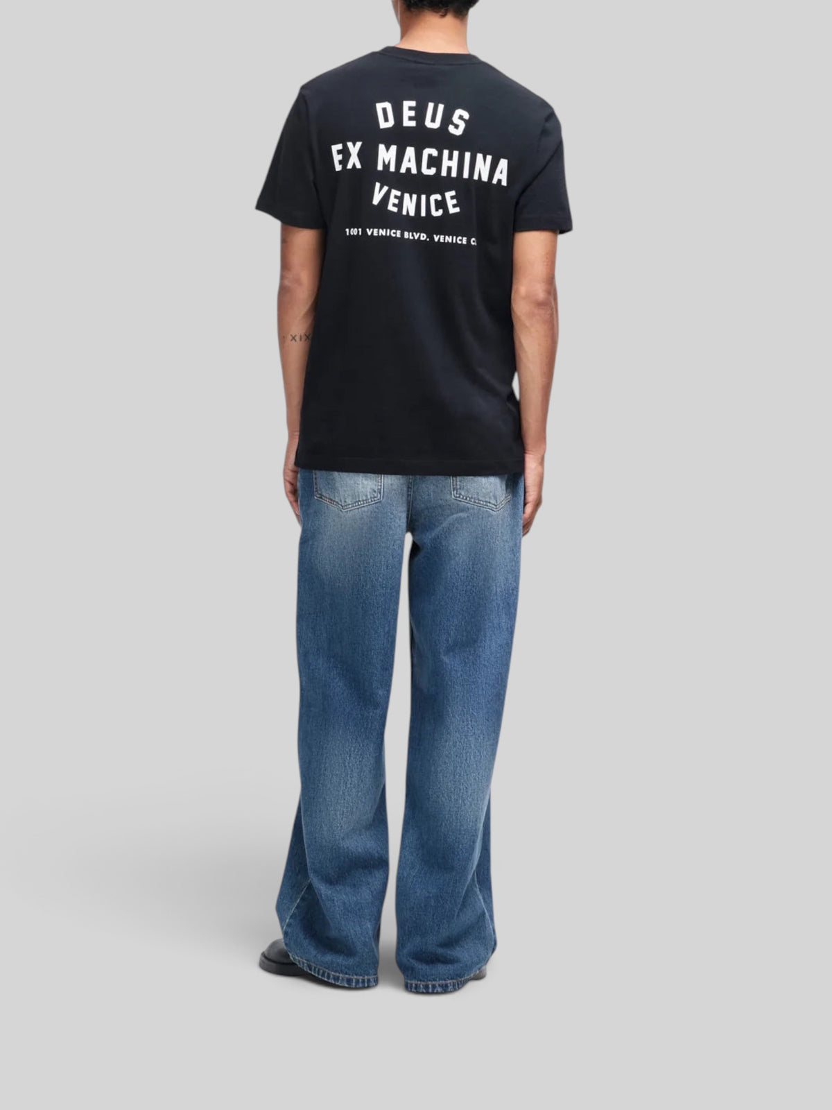 Baffle Haus Venice Skull black organic cotton t-shirt with white back graphic print worn by a man with blue jeans