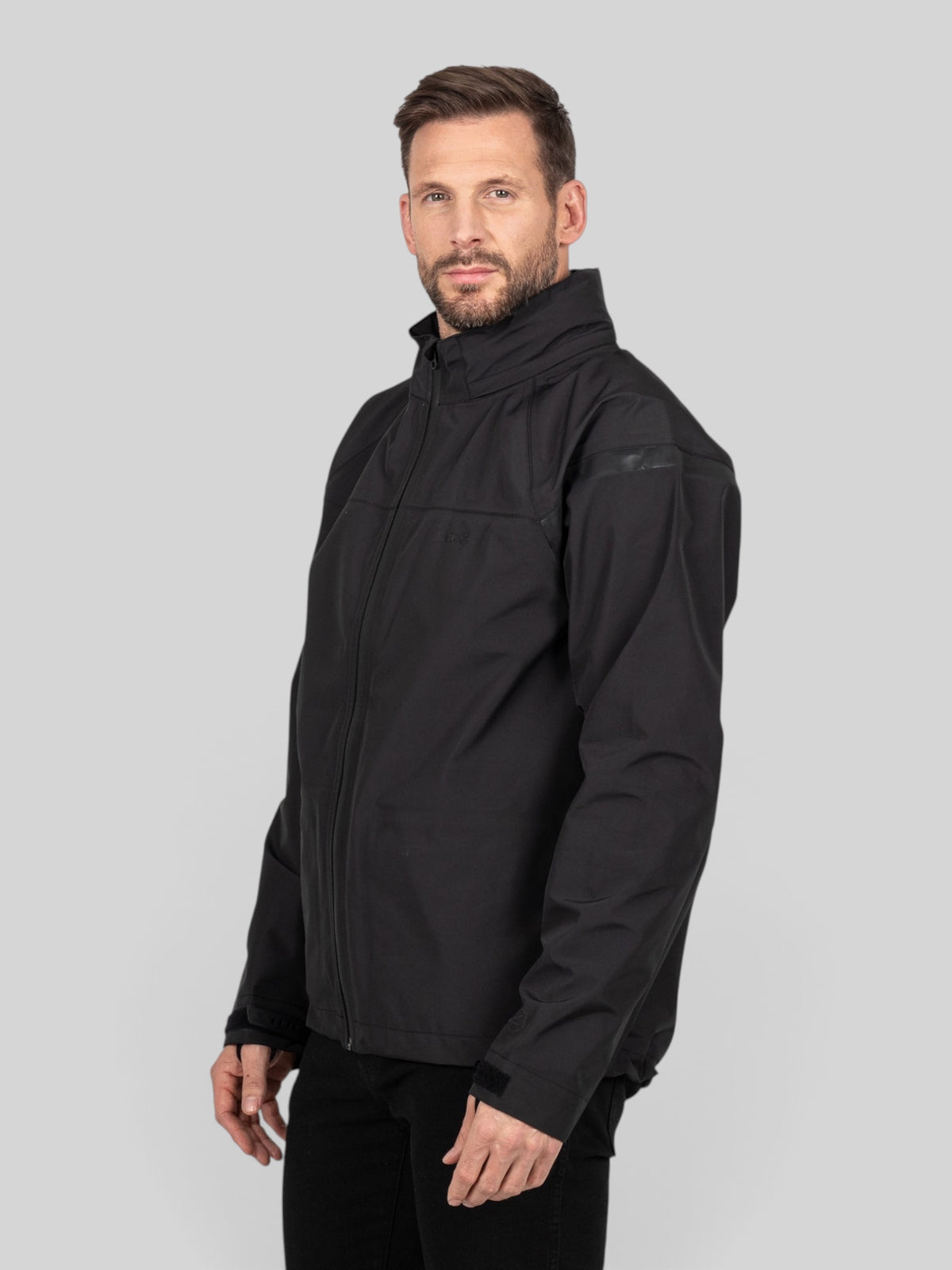 Baffle Haus Welbeck MK2 waterproof black motorcycle overjacket worn by a man, featuring a high collar and sleek fit.