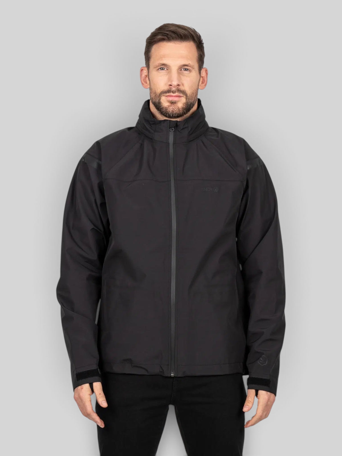 Baffle Haus Welbeck MK2 waterproof black motorcycle overjacket with high collar and adjustable cuffs on a male model.