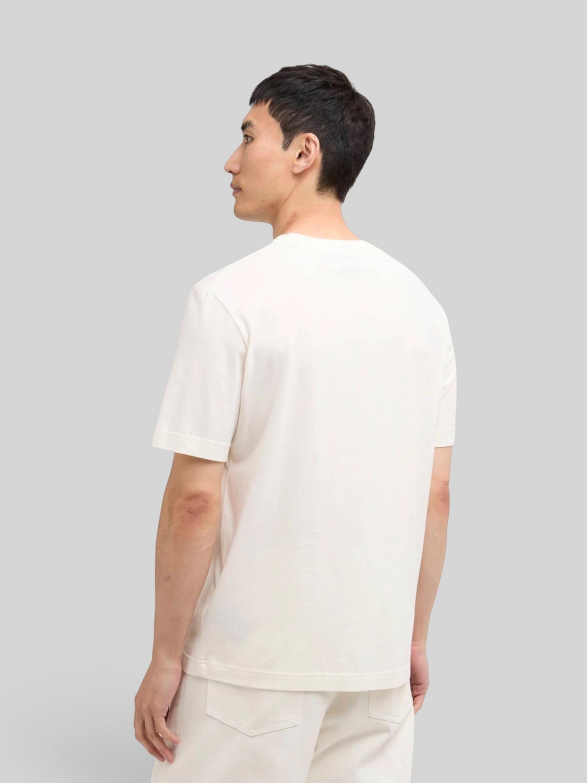 Back view of a man wearing a Baffle Haus whisper white cotton t-shirt with a relaxed fit and open cuffs.