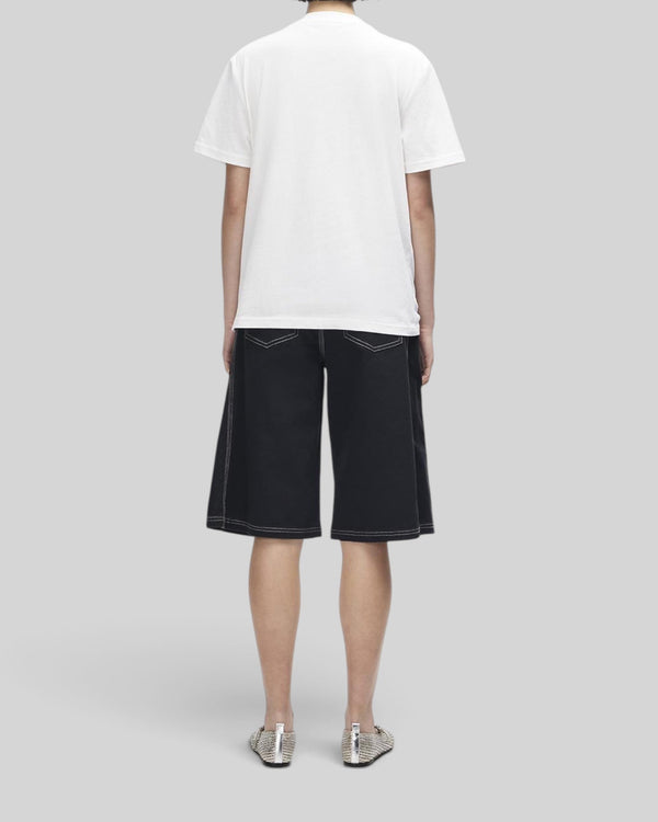 Baffle Haus model wearing a white Deus A110 tee and black shorts with contrast stitching, back view.
