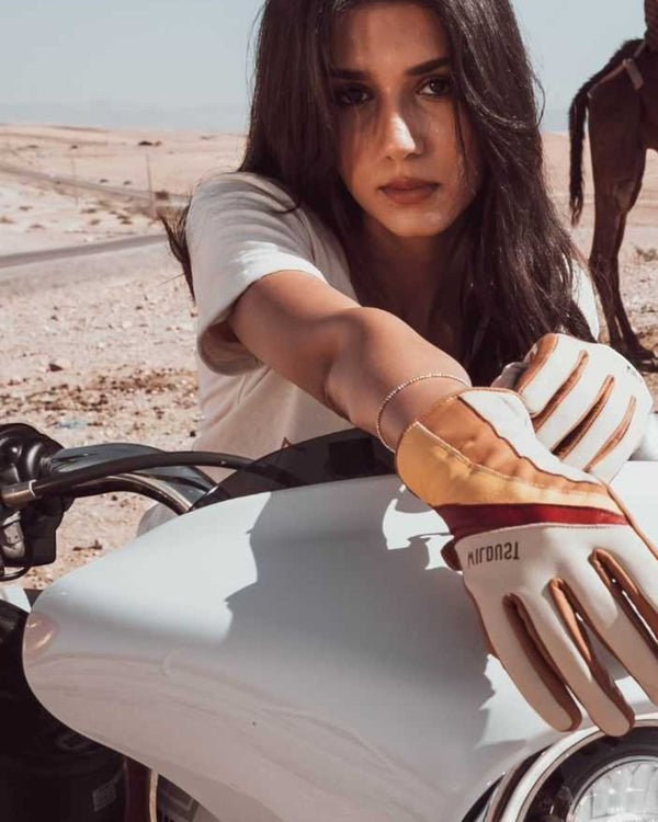 Baffle Haus Wildust 70s stripe leather motorcycle gloves in white and red worn by a woman on a white motorcycle