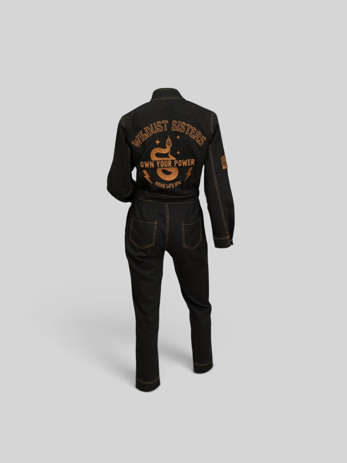Baffle Haus Wildust black cotton aviator jumpsuit with camel stitching and Own Your Power embroidery on the back