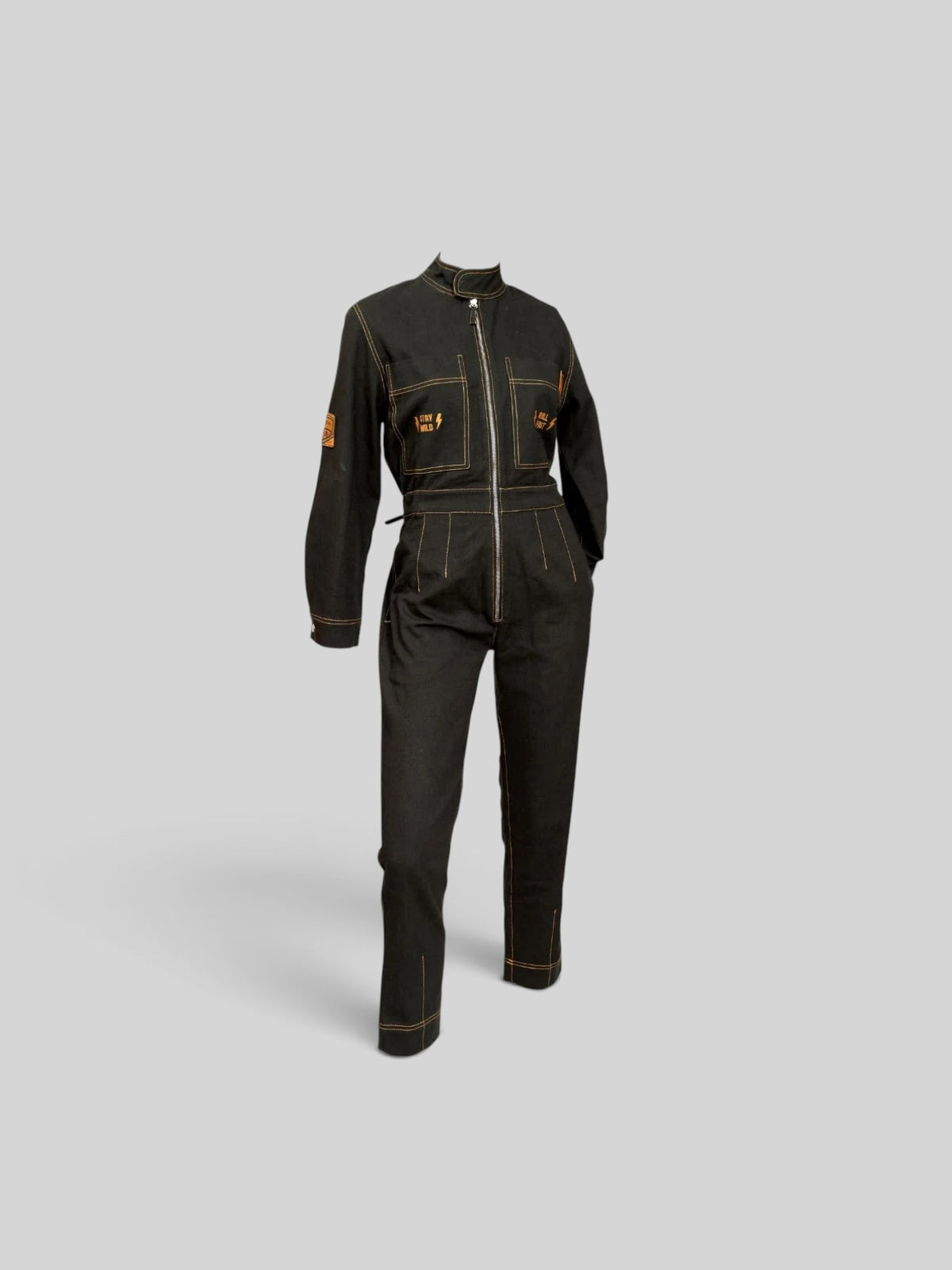 Baffle Haus Wildust black cotton aviator jumpsuit with camel stitching, chest embroidery, and tapered fit.