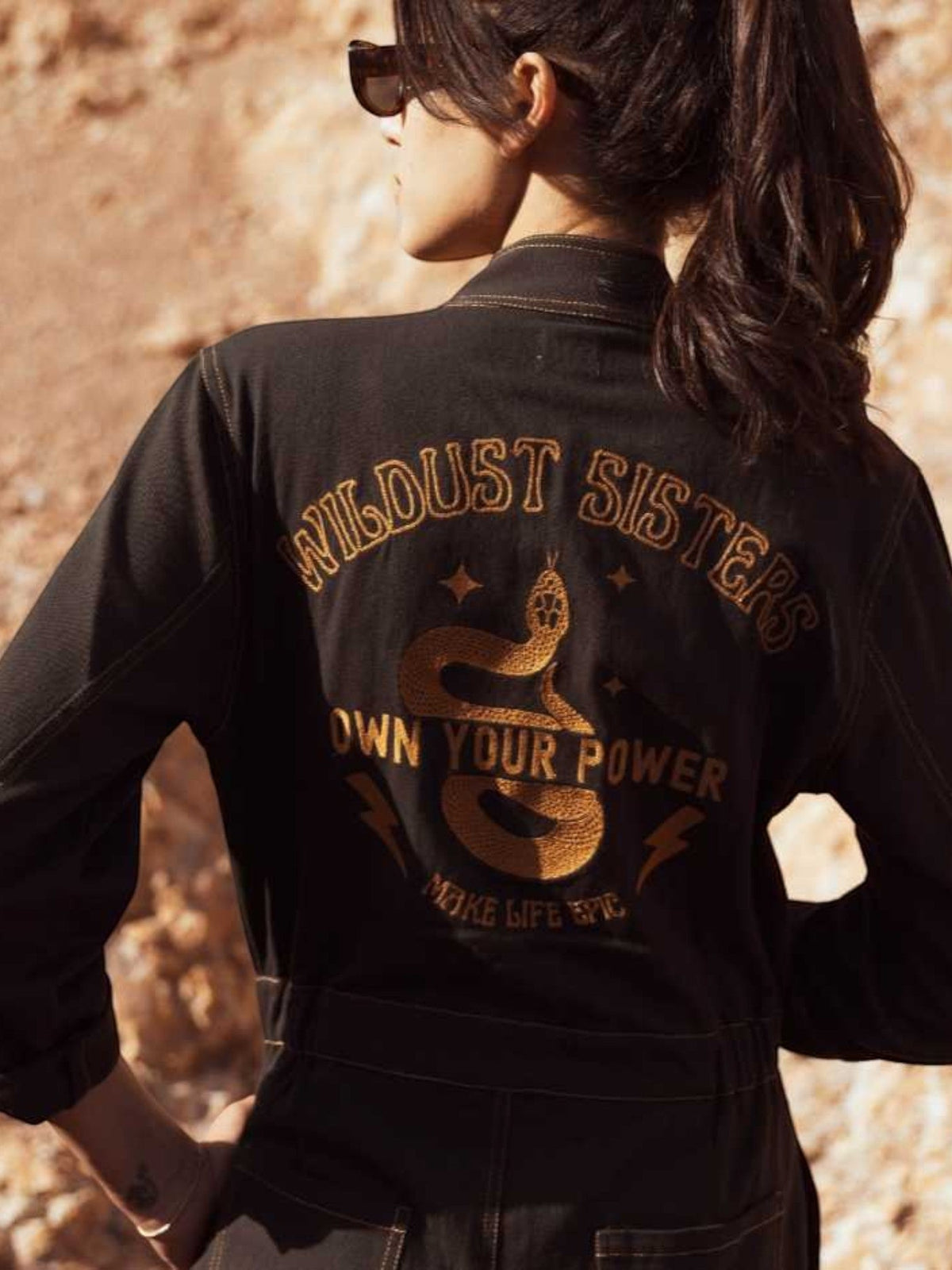 Baffle Haus Wildust black cotton aviator jumpsuit featuring Own Your Power snake embroidery on the back