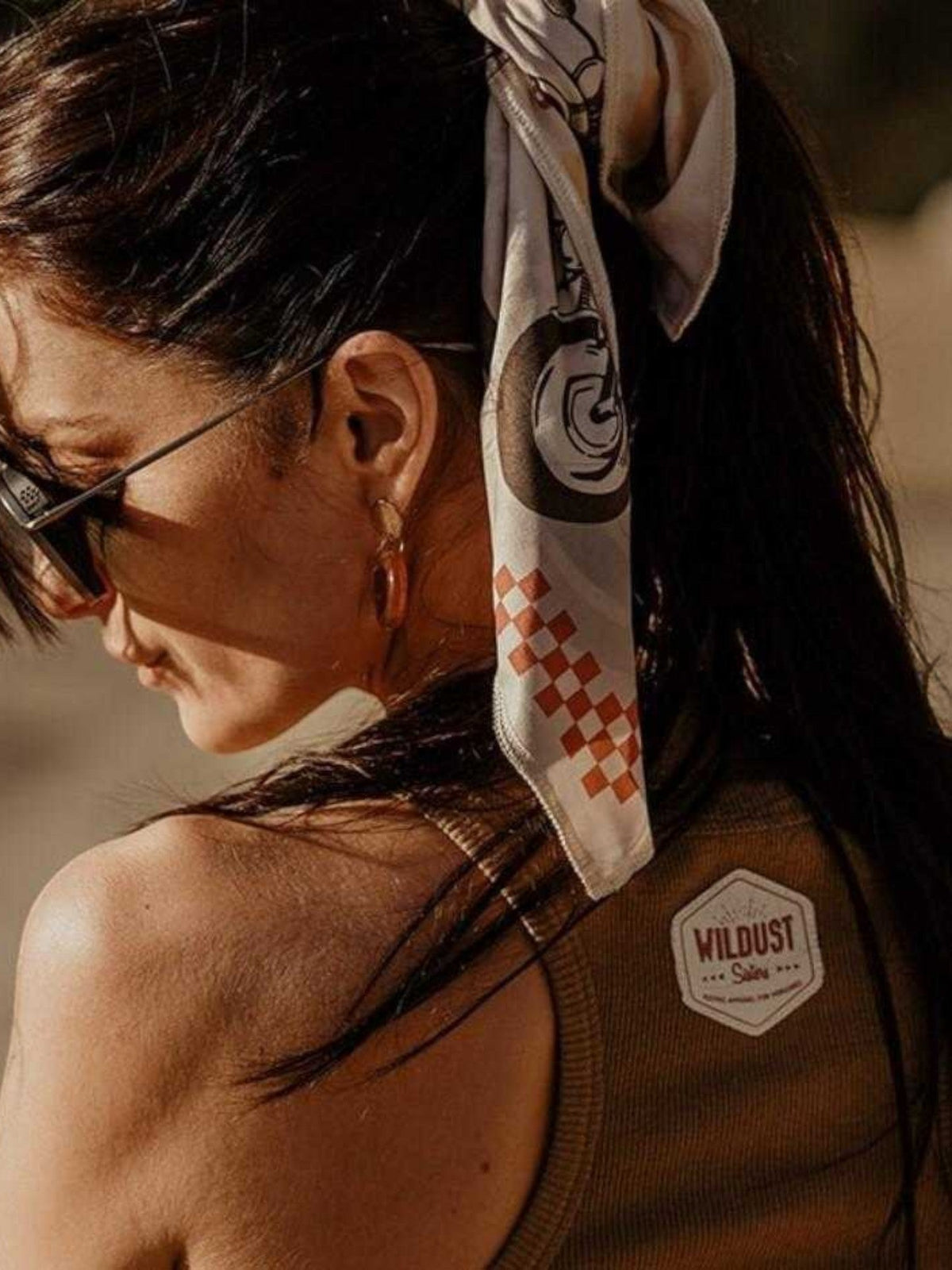 Baffle Haus Wildust vintage racer scarf in ecru with racing stripes worn as a bandana by a woman outdoors