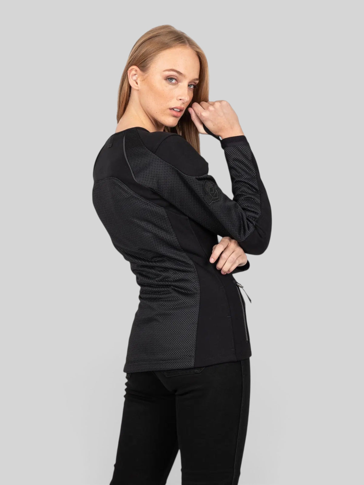A female rider wearing a black Baffle Haus Womens Urbane Pro MK3 motorcycle jacket with breathable mesh panels.