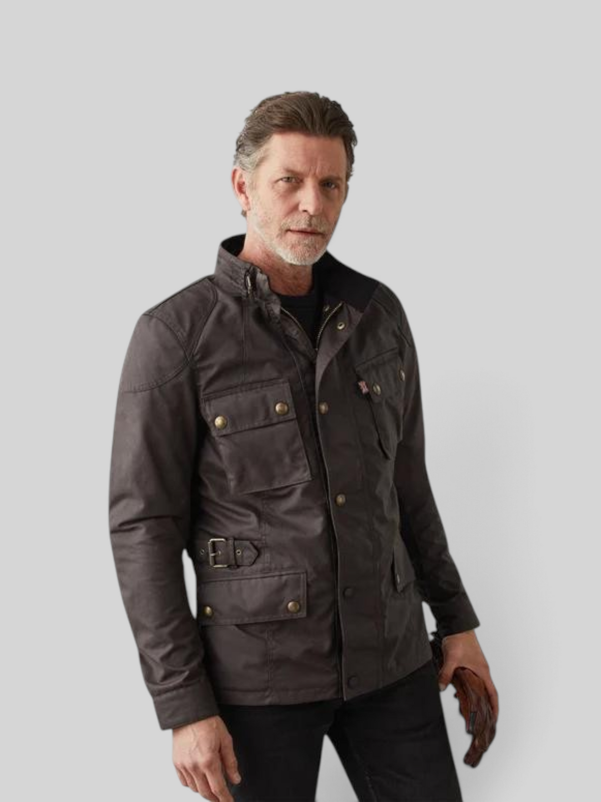A man wearing a Baffle Haus Crosby mahogany waxed cotton motorcycle jacket with antique brass hardware and waist buckle