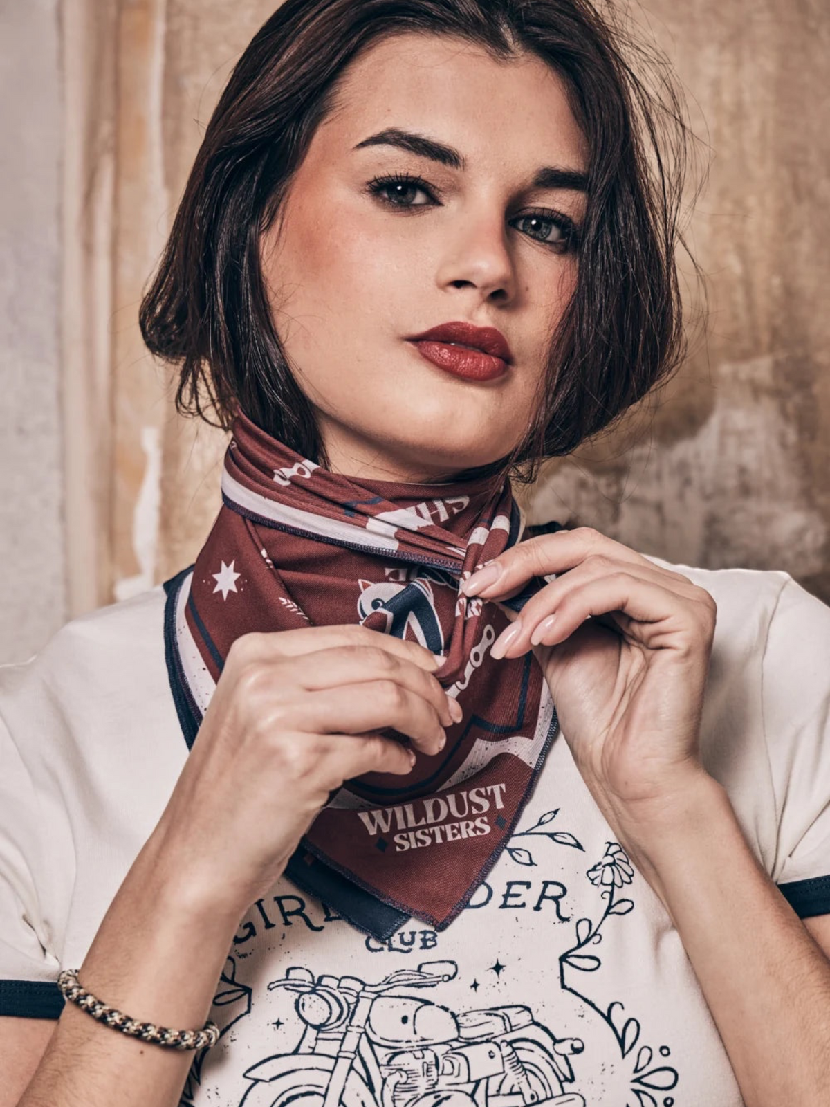Baffle Haus Victory motorcycle scarf in blue and terracotta with retro racing graphics worn as a neck bandana