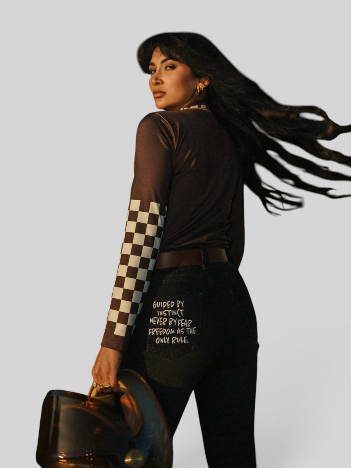 Baffle Haus brown long sleeve Lycra top with checkered sleeves worn by a woman outdoors at sunset