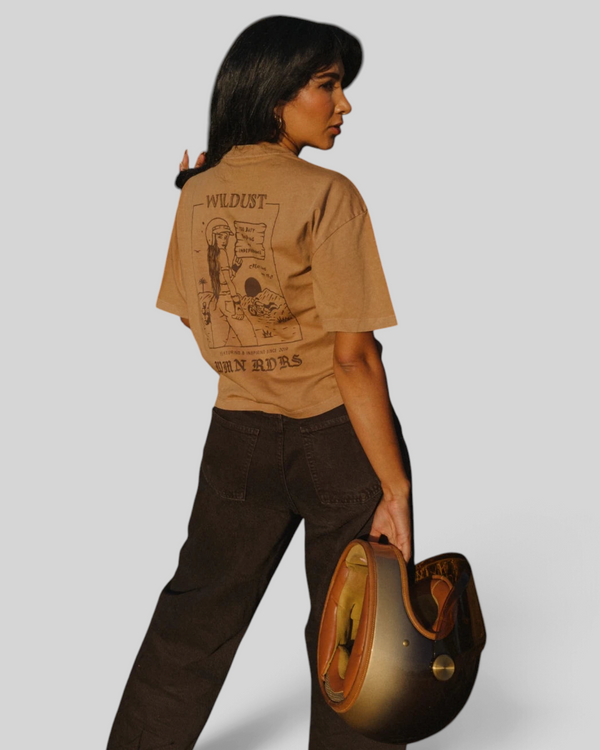 Baffle Haus khaki 100% cotton cropped T-shirt with back graphic print, worn by a woman holding a vintage helmet.
